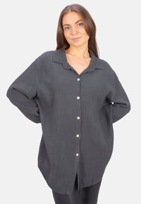 Gray, button-up shirt made of textured fabric; features a collared neck, long sleeves, and side slits at the hem for a relaxed fit.