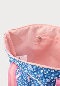 Τσάντα tote από καπιτονέ ύφασμα με μπλε εξωτερικό  μέρος που διαθέτει λουλουδένια και καρτουνίστικα σχέδια, και ροζ εσωτερικό με τσεπάκι με φερμουάρ.