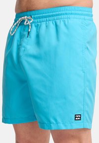 Ανοιχτομπλε μαγιό από γρήγορο υλικό στεγνώματος, με ελαστική μέση και κορδόνι, και λάδι και λογότυπο στη κάτω αριστερή γωνία.