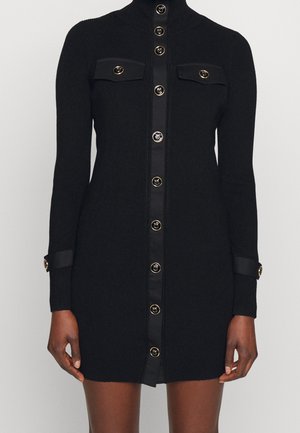 Black long-sleeve button-up mini dress with gold-trimmed black buttons, two chest pockets, and cuff straps on sleeves.