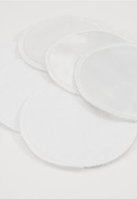 Set van zes ronde, witte katoenen borstvoedingpads met een zachte textuur en gestikte randen, ontworpen voor vochtabsorptie.
