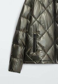 Manche de doudoune matelassée métallique verte avec couture diagonale et poche zippée verticale sur fond blanc.