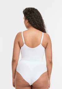 Body bianco con spalline regolabili, texture liscia e design a gamba alta. Retro senza cuciture con dettagli minimi.