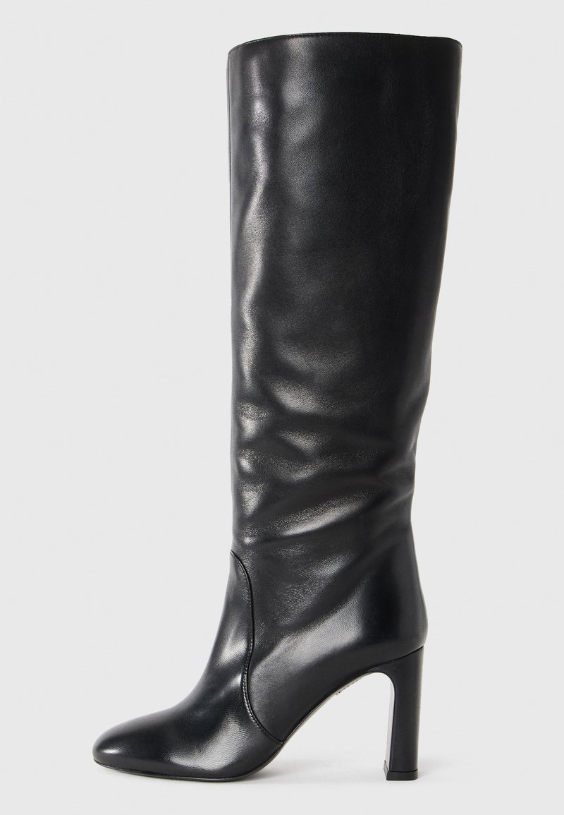 Stivale in pelle nera al ginocchio con punta affusolata e tacco alto a blocco, texture liscia con leggere pieghe naturali.