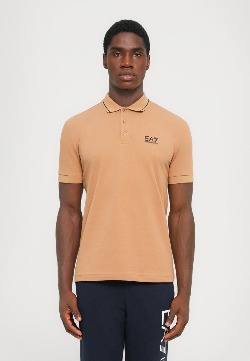 Tan polo skjorte med to knapper, kontrasterende krage og EA7-logo. Glatt stoff, korte ermer og en tettsittende design.