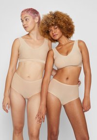 Beige seamless bra and high-waisted panties made of smooth fabric, featuring a simple design and wide straps for comfort and support.