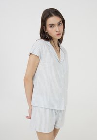 Set di pigiama in cotone a righe azzurre e bianche, con maniche corte, una camicia con bottoni e pantaloni corti abbinati con elastico in vita.