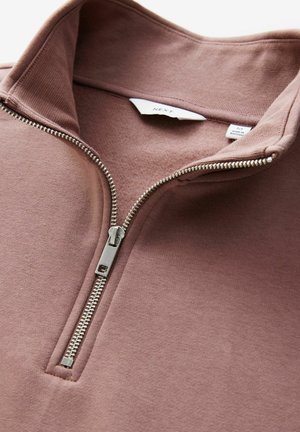 Półzapinany pulower w miękkim odcieniu mauve, z metalowym zamkiem błyskawicznym, prążkowanym kołnierzem oraz gładką teksturą z metką przyszytą wewnątrz.