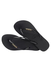 Zwarte rubberen teenslippers met gestructureerde zolen en dunne banden, met het Havianas-logo in het goud op één band.