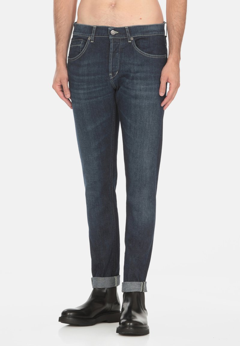 Jeans in denim blu scuro con vestibilità slim, design a cinque tasche e orli arrotolati. Presentano una chiusura con bottone e cuciture in contrasto.