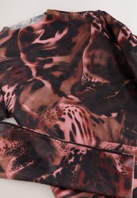 Przezroczysta bluzka z długim rękawem w ciemnych odcieniach z abstrakcyjnymi czerwonymi i różowymi wzorami, charakteryzująca się gładką, lekką teksturą oraz subtelnymi detalami szwów.