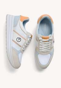 Baskets bleu clair et beige avec des accents blancs, tissu texturé, détails orange et un logo rond sur le côté. Semelle plateforme.