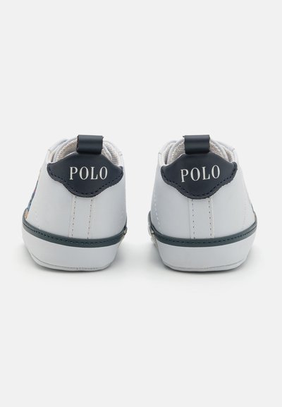 Bílé tenisky s námořnickými modrými akcenty, kožený materiál, zaoblený tvar a logo "POLO" na patě. Texturovaný povrch a detaily prošívání.