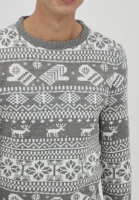 Grå strikket sweater med et hvidt Fair Isle mønster med rensdyr, snefnug og geometriske former. Ribbet halsudskæring og manchetter.