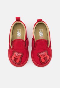 Zapatos tipo slip-on de lona roja con un diseño de osito de goma en la puntera. Presentan laterales elásticos y un forro interior beige para mayor comodidad.