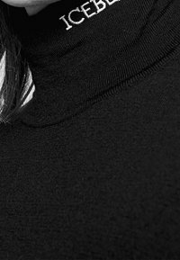 Schwarzer Rollkragenpullover mit geripptem Textur und weißer "ICEBERG" Schriftzüge am Kragen. Glatte Stoffqualität mit taillierter Passform.