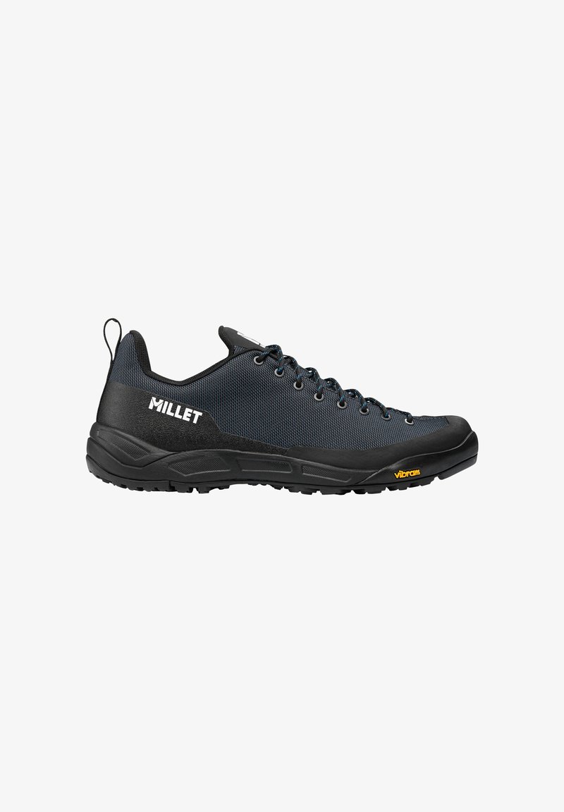 Chaussure de randonnée basse noire et bleu foncé avec des lacets, logo "MILLET" sur le côté, et semelle Vibram, présentée en profil latéral sur fond blanc.