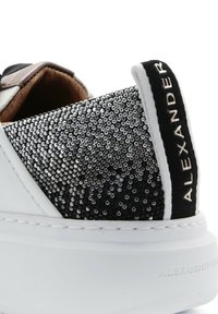 Sneaker bianco con una tomaia testurizzata nera e argento in strass e suola in gomma bianca. Presenta un accento nero sul tallone con branding.