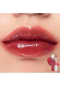 Couleur à lèvres rouge profond et brillant sur des lèvres pleines, mettant en valeur une texture lisse. Un tube et un applicateur sont présentés à côté dans un design élégant.