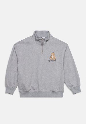 Svetlosivá mikina so zipsom do štvrtej, s malým tedi medvedíkom a textom "Moschino" na ľavej strane hrudníka.