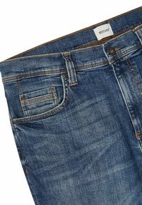 Jeans de mezclilla azul oscuro con un corte clásico, con costuras naranjas, cierre de botón metálico y detalles en los bolsillos frontales.