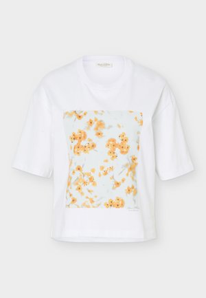 Camiseta blanca de manga corta con una estampado cuadrado en el frente de pequeñas flores naranjas sobre un fondo azul claro.