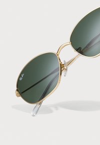 Gold metal aviator sunglasses with green lenses, featuring a slim profile, clear nose pads, and a minimalist design.
