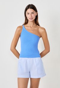 Top azzurro chiaro a coste con una silhouette aderente, abbinato a pantaloni corti a righe bianche e blu con una vestibilità rilassata e fascia elasticizzata in vita.