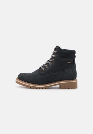 Schwarze Wildleder-Ankle-Boots mit Schnürdesign, kontrastierender brauner Gummisohle, gepolstertem Kragen und Logodetail an der Seite.