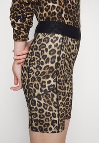 Szorty rowerowe w wzór lamparta wykonane z elastycznej tkaniny, z czarnym elastycznym pasem w talii i czarnymi detalami stębnowania wzdłuż boków.