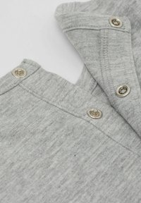 Szary bawełniany strój z złożonym kołnierzykiem, dwoma zatrzaskami i subtelną fakturą. Skupia się na funkcjonalności i detalach wzornictwa.