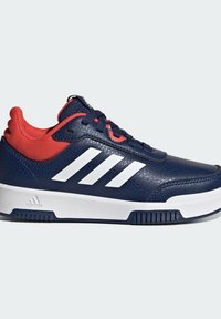 Marineblauwe sneakers met een gestructureerde leren bovenkant, een rode mesh kraag, een wit drie-streepdessin en een witte rubberen zool.