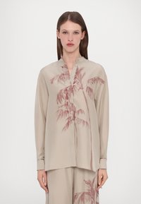 Blusa beige a maniche lunghe in tessuto leggero con design di palme in rosa tenue, dotata di colletto alla mandarino e chiusura con bottoni.