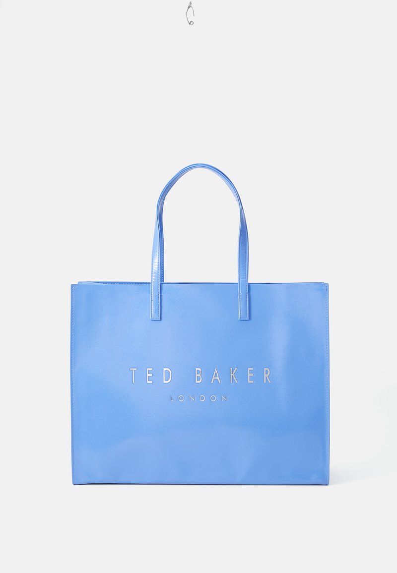 Világoskék, fényes anyagból készült bevásárlótáska, két fogantyúval és ezüstszínű logóval az elején, amelyen a "TED BAKER" és "LONDON" felirat található.