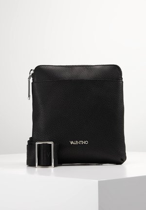 Black leather crossbody bag with a textured surface, featuring a silver zipper and a branded strap buckle. Compact rectangular design.