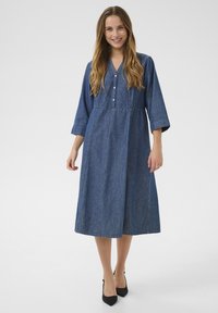 Jeansklänning med knälång design, trekvartslånga ärmar, knappslå och en rynkad midja i mörkblått tyg.