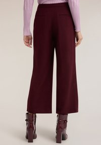Bordowe spodnie o szerokich nogawkach o gładkiej fakturze z tylnymi kieszeniami. Połączone z błyszczącymi bordowymi botkami na obcasie typu słupek z zamkami błyskawicznymi.