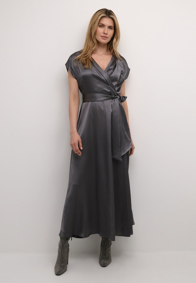 Langes, satiniertes Wickelkleid in Dunkelgrau mit kurzen Ärmeln und einem gebundenen Gürtel in der Taille, kombiniert mit metallischen Stiefeletten.
