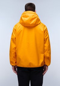 Žlutá vodotěsná bunda s kapucí, se hladkým povrchem, elastickými manžetami a uvolněným střihem, viděná ze zadní strany.
