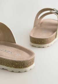 Plattform-Sandalen mit beigem Obermaterial, weichem, strukturiertem Fußbett und contrastierendem, korkähnlichem Zwischensohlenmaterial, ausgestattet mit einer weißen, schaumigen Außensohle mit gewelltem Rand.
