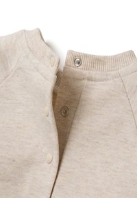 Beige katoenen kledingstuk met geribde kraag, drukknoopsluiting en een gestructureerd oppervlak, met een minimalistisch ontwerp en zachte, ademende stof.