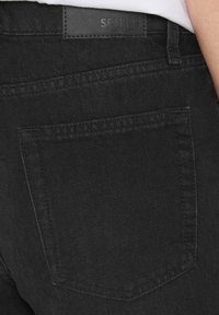 Schwarze Jeans aus Denim mit einer Gesäßtasche, strukturiertem Stoff und einem SENSES-Tag mit matter Oberfläche am Bund.