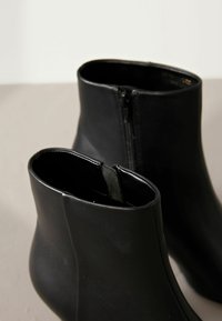 Stivaletti neri realizzati in pelle liscia, con cerniera laterale e bordo superiore elastico, dal design snello e affusolato.