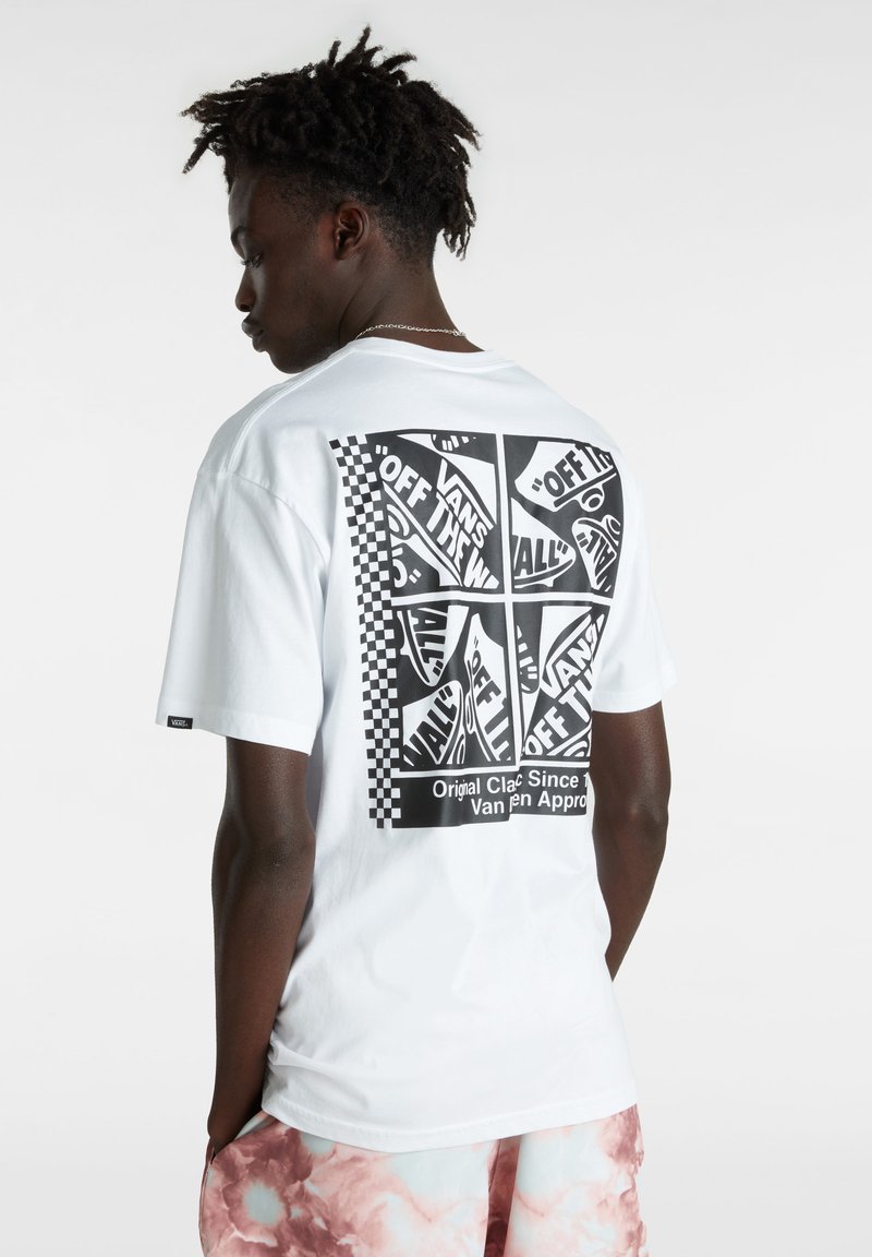 Camiseta de algodón blanca con un gran gráfico negro en la parte posterior que presenta logotipos y un patrón de tablero de ajedrez. Mangas cortas, ajuste relajado.