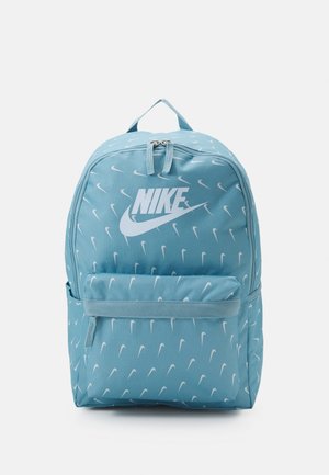 Světle modrý batoh s bílými logy a vzorem swoosh značky Nike, má přední kapsu, nastavitelné popruhy a horní držadlo.