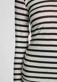 Zwart-wit gestreept t-shirt met lange mouwen, gemaakt van zachte, gestructureerde stof. Heeft gelijkmatig verdeelde horizontale strepen.
