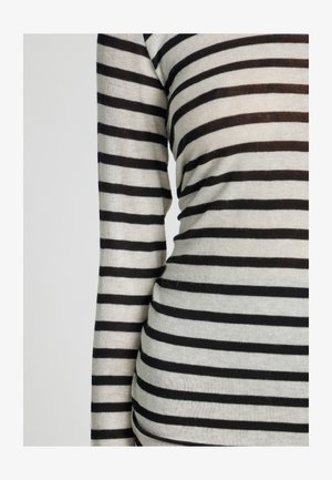 Prugasta crno-bijela majica dugih rukava izrađena od mekog, teksturiranog materijala. Ima ravnomjerno raspoređene horizontalne pruge.