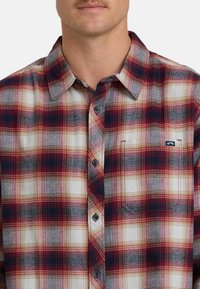 Camicia di flanella a quadri in bianco, rosso e blu navy. Design con bottoni e taschino sul petto. Tessuto morbido con un aspetto tessuto e strutturato.