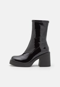 Stivaletti alla caviglia in pelle verniciata nera con punta quadrata, tacco alto a blocco e parte superiore a coste; finitura elegante e lucida con un design minimal.