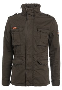 Olivgrön jacka i hållbar tyg, med hög krage, två bröstfickor och två sidofickor. Inkluderar axelremmar och logopatch.